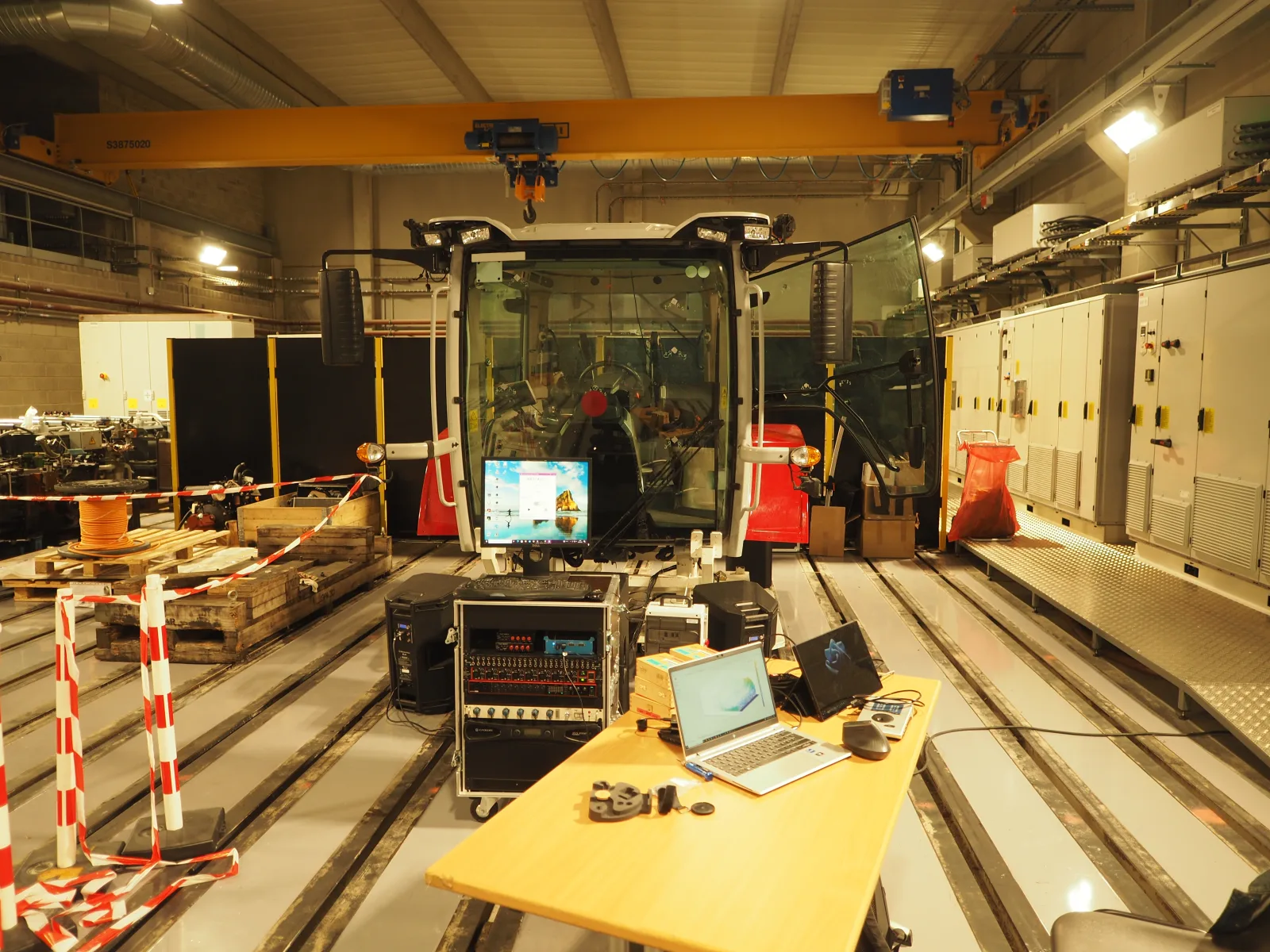 Poste d'acquisition acoustique face à une cabine d'engin sur banc d'essai, rack de mesure, écran d'analyse et ordinateur affichant un spectre
