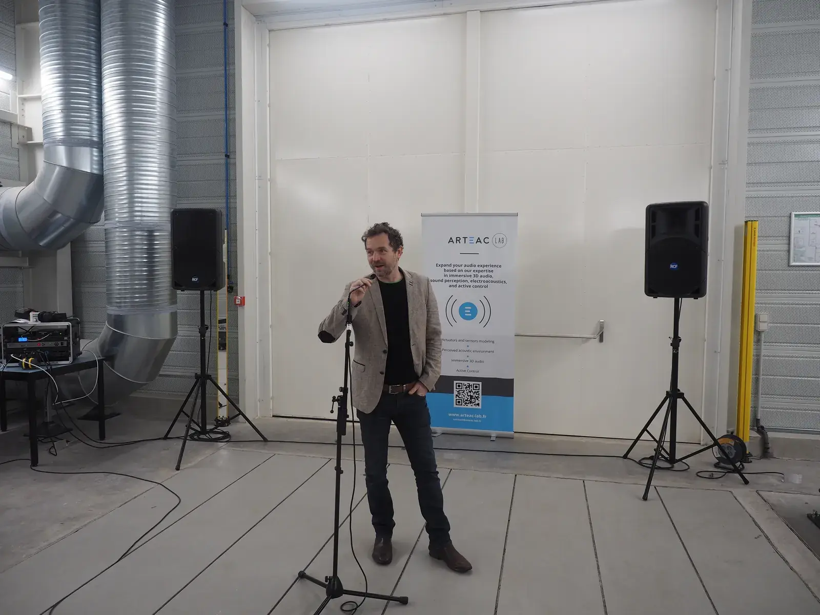 Présentation d'ARTEAC-LAB au micro devant un stand, en halle d'essais