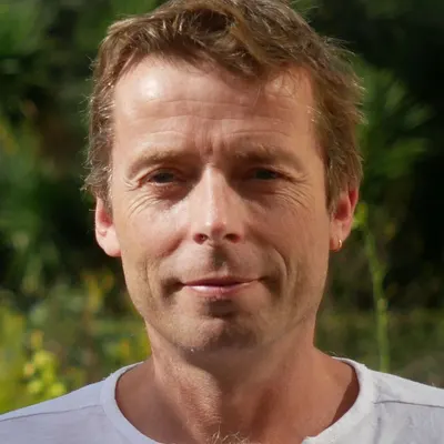 Portrait de Christophe Lambourg, en extérieur devant de la végétation.