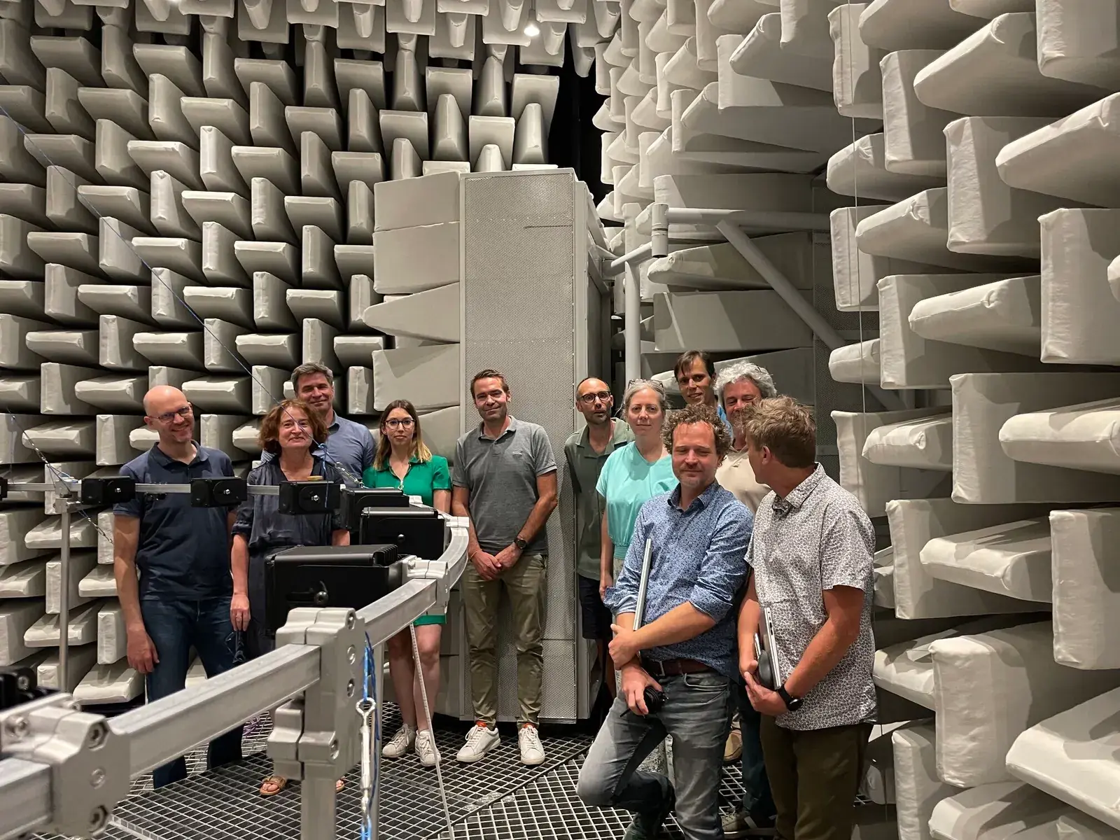Groupe de personnes dans une très grande chambre anéchoïque, antenne de microphones au premier plan